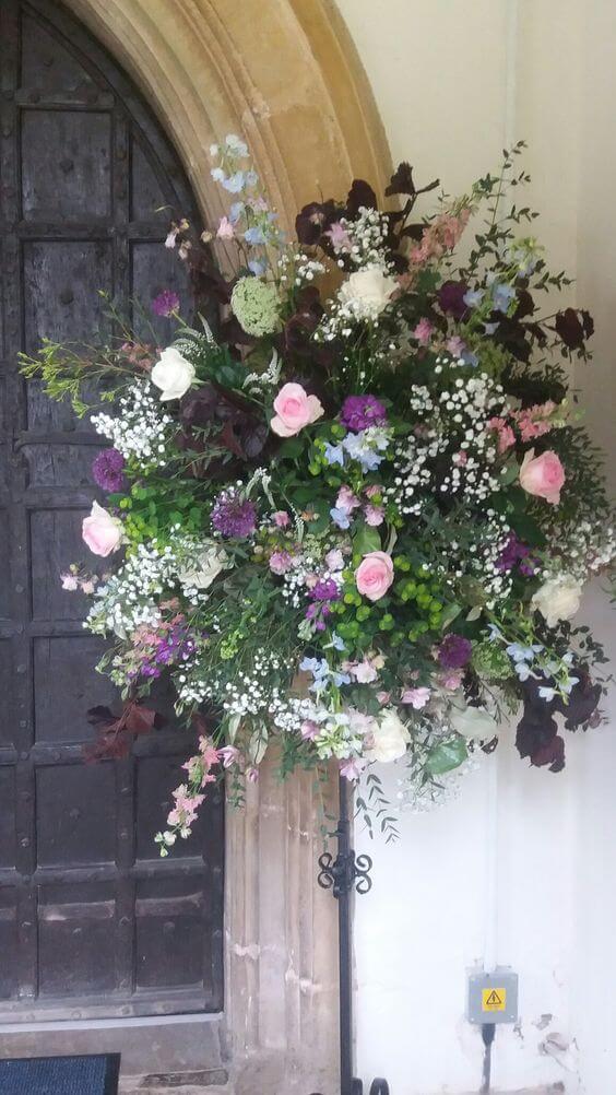 Pink and cream country pedestal flowers outside church